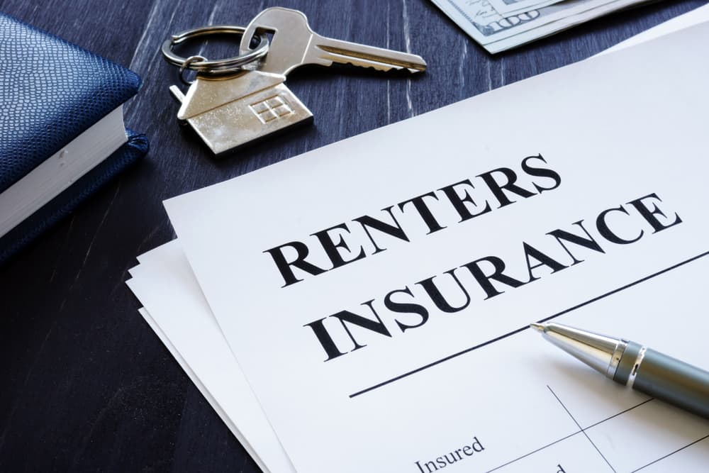 A clipboard with renters insurance listed on it next to a set of keys.