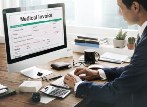 Man in suit sitting at desk at computer displaying medical invoice