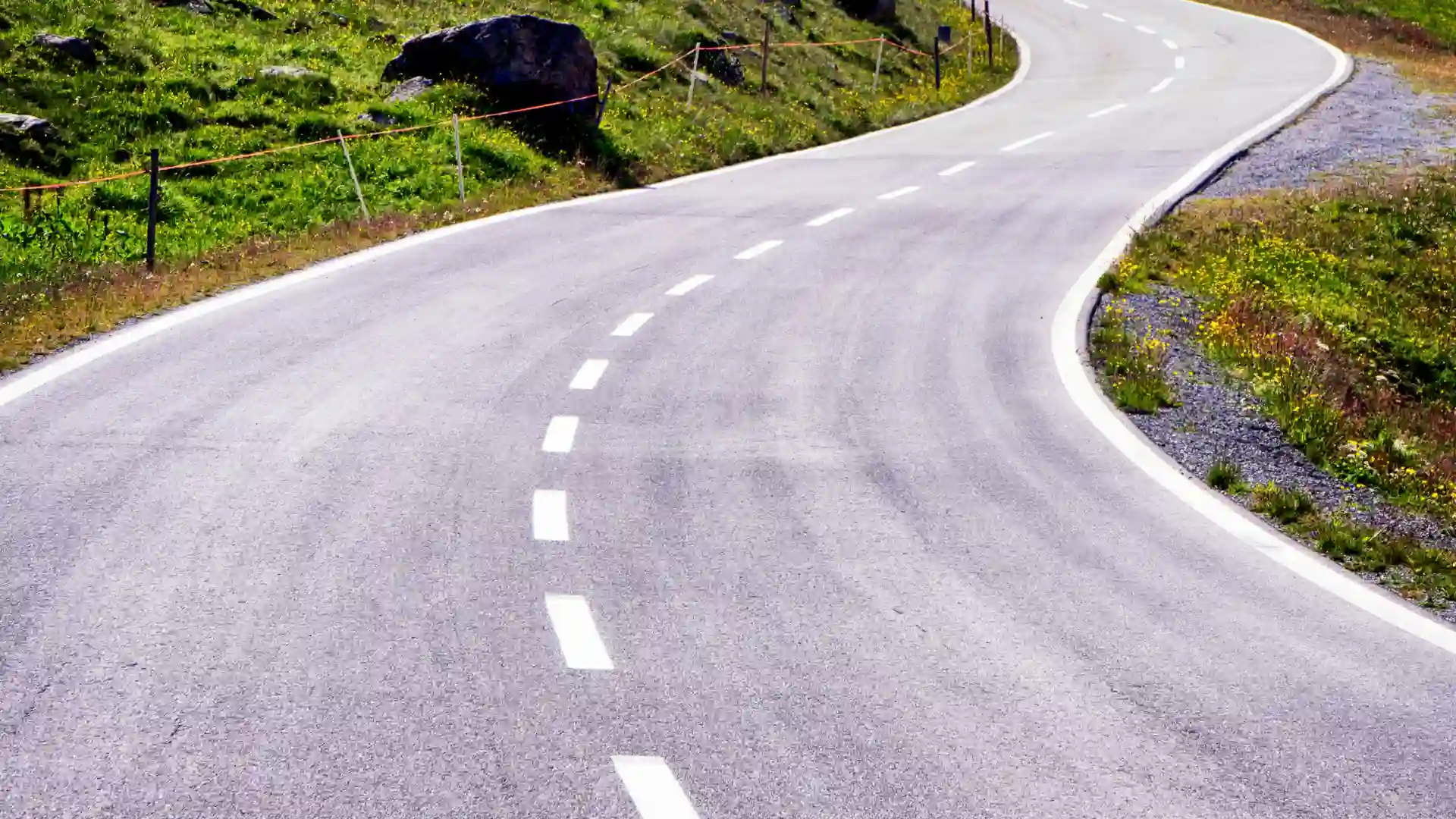 Curving empty road with dashed lane markings.